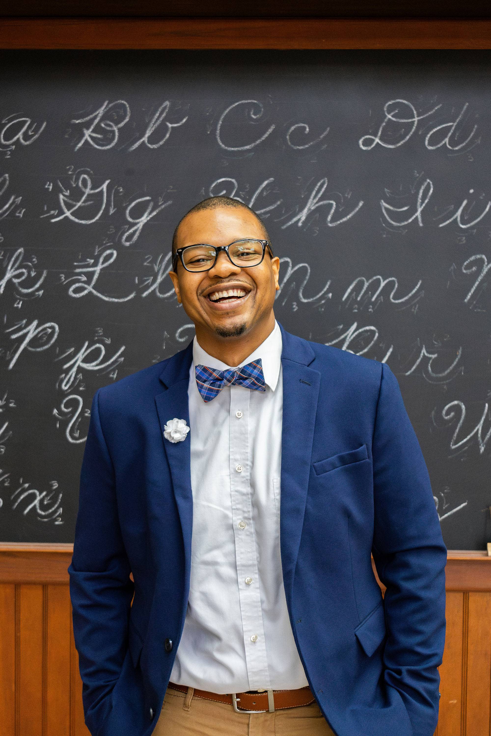 Dar Mayweather standing in front of a chalkboard with writing in chalk